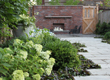 An angle on the lush verge surrounding the brick fireplace